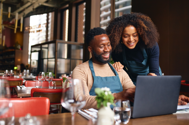 Male and female restaurant coworkers looking at a laptop together