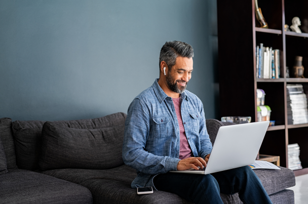 Smiling male working on a laptop in a home setting