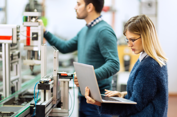 Close up of a female reviewing something on a laptop with a coworker looking at the machine behind her