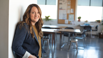 Close-up of a woman smiling while leaning against a wall.